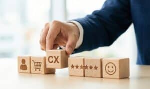 Customer experience concept with wooden cubes showing customer icon, cart, CX, ratings, and smile emoji.